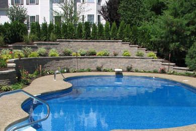 This is an example of a large back custom shaped swimming pool in Boston with natural stone paving.
