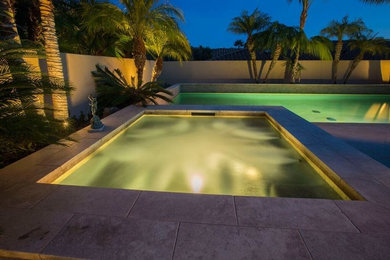 Modelo de piscinas y jacuzzis actuales grandes rectangulares en patio trasero con losas de hormigón