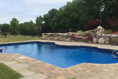Large traditional back custom shaped swimming pool in Minneapolis with brick paving.