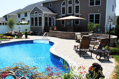 Modelo de casa de la piscina y piscina infinita a medida en patio trasero con adoquines de piedra natural