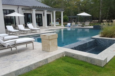 Идея дизайна: большой прямоугольный бассейн-инфинити на заднем дворе в современном стиле с фонтаном и покрытием из каменной брусчатки