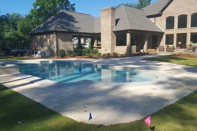 Ejemplo de piscinas y jacuzzis naturales actuales de tamaño medio a medida en patio trasero con adoquines de hormigón