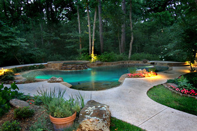 Large island style backyard stamped concrete and kidney-shaped natural hot tub photo in Houston