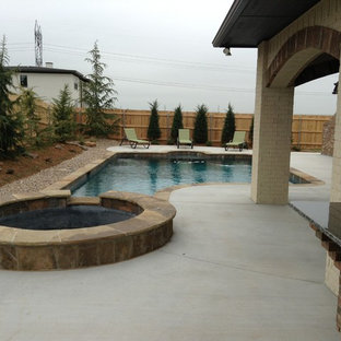Design ideas for a small traditional backyard custom-shaped pool in Oklahoma City with a hot tub and concrete slab.