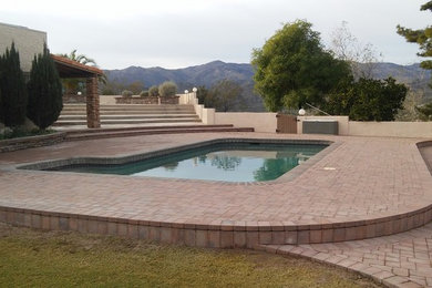 Example of a classic backyard stone and l-shaped pool design in Other