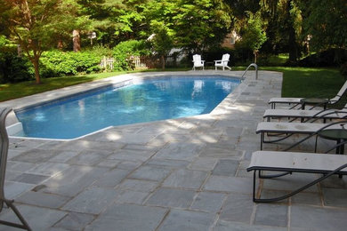 Example of a mid-sized classic backyard stone and custom-shaped pool design in New York