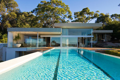 Diseño de piscina alargada actual grande rectangular en patio trasero con entablado