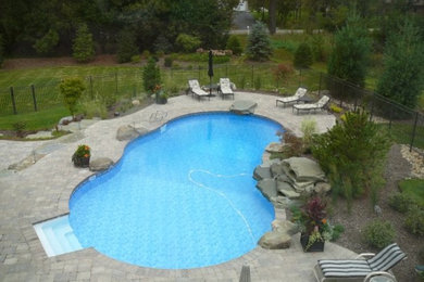 Foto de piscina con fuente natural grande tipo riñón en patio trasero con adoquines de piedra natural