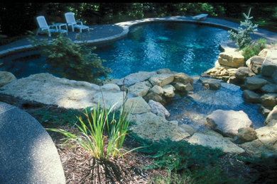 Diseño de piscina con fuente natural de tamaño medio a medida en patio trasero con adoquines de piedra natural