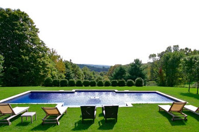 Large modern back custom shaped natural swimming pool in New York with natural stone paving.