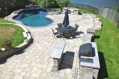 Modelo de piscina con fuente natural grande a medida en patio trasero con adoquines de piedra natural