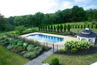 Elegant backyard concrete paver and custom-shaped pool photo in New York