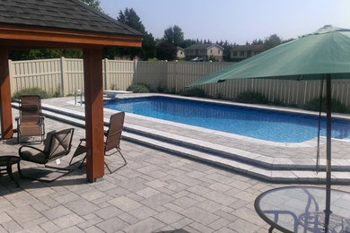 Imagen de piscina tradicional de tamaño medio rectangular en patio trasero con adoquines de hormigón