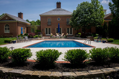 Imagen de piscina alargada clásica grande rectangular en patio trasero con suelo de hormigón estampado