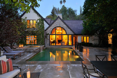 Imagen de piscina alargada clásica rectangular en patio trasero con adoquines de hormigón