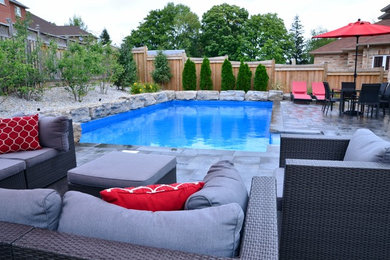 Foto de piscina alargada clásica renovada de tamaño medio rectangular en patio trasero con adoquines de hormigón