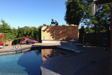 Modelo de piscina con fuente alargada clásica renovada de tamaño medio a medida en patio trasero con adoquines de ladrillo
