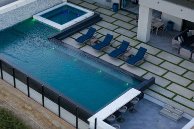 Imagen de piscinas y jacuzzis infinitos actuales rectangulares en patio trasero con adoquines de hormigón