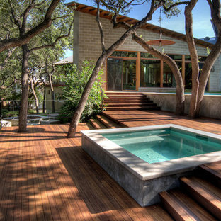 Idee per una piscina a sfioro infinito design rettangolare dietro casa con una vasca idromassaggio e pedane