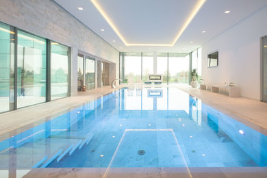 This is an example of a large contemporary indoor rectangular swimming pool in Dusseldorf with tiled flooring and a water feature.