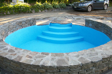 Diseño de piscina tradicional renovada redondeada con adoquines de piedra natural