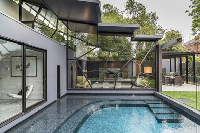 Imagen de piscina actual de tamaño medio rectangular en patio trasero con suelo de baldosas