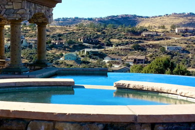 Huge tuscan backyard stone and rectangular infinity hot tub photo in Phoenix