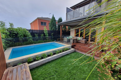 Imagen de piscina natural minimalista grande rectangular en patio trasero con paisajismo de piscina y entablado