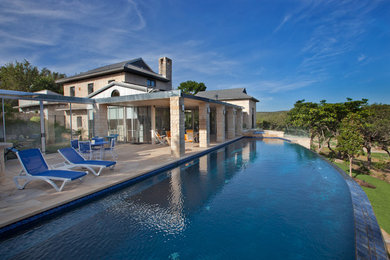 Trendy stone and custom-shaped infinity pool photo in Austin