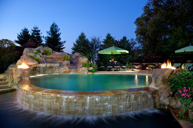 Immagine di una piscina naturale tropicale personalizzata con un acquascivolo