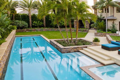 Ejemplo de piscinas y jacuzzis alargados exóticos grandes rectangulares en patio trasero con adoquines de hormigón