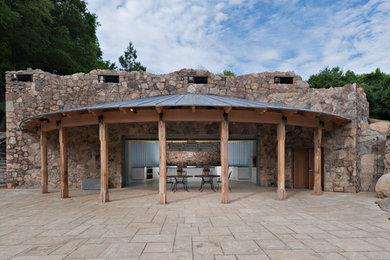 Ejemplo de casa de la piscina y piscina natural rústica grande a medida en patio trasero con adoquines de piedra natural