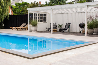 Inspiration for a large transitional backyard rectangular natural pool remodel in Copenhagen with decking