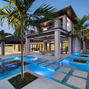 Ispirazione per una piscina tropicale personalizzata dietro casa con cemento stampato