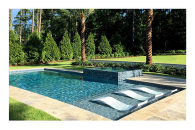 Design ideas for a medium sized contemporary back custom shaped swimming pool with natural stone paving.