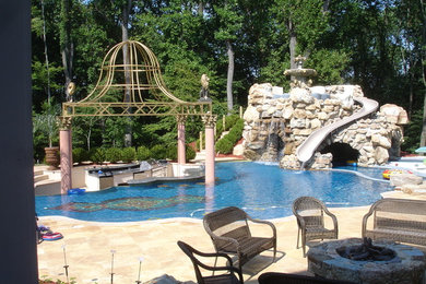 Diseño de piscina con tobogán contemporánea grande a medida en patio trasero con adoquines de piedra natural