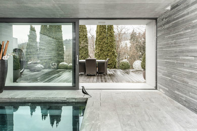 Réalisation d'une piscine intérieure naturelle design de taille moyenne et rectangle avec un bain bouillonnant et des pavés en pierre naturelle.