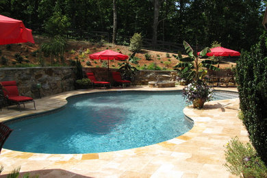 Ejemplo de piscina tradicional grande a medida en patio trasero con adoquines de piedra natural