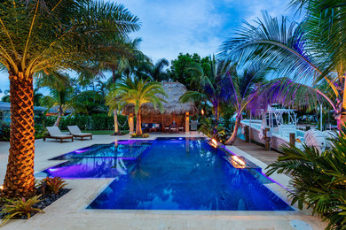 Mid-sized island style backyard stone and rectangular infinity hot tub photo in Miami