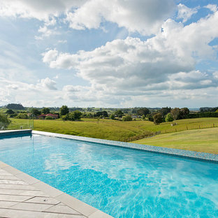 Esempio di una piscina a sfioro infinito contemporanea rettangolare dietro casa con pedane