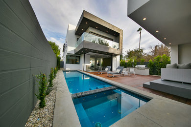 Ejemplo de piscina alargada minimalista rectangular en patio trasero con losas de hormigón