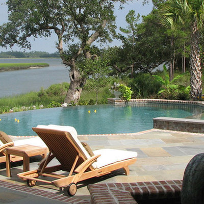 Hot tub - large tropical backyard brick and round aboveground hot tub idea in Charleston