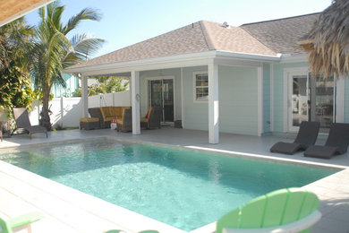 Modelo de piscina alargada costera de tamaño medio rectangular en patio trasero con adoquines de hormigón