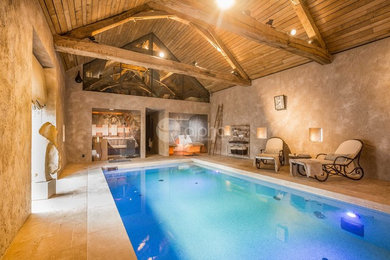 Esempio di una grande piscina coperta monocorsia stile rurale rettangolare con una vasca idromassaggio e pavimentazioni in pietra naturale