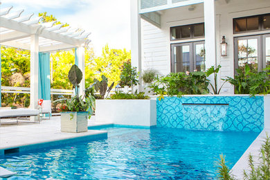 Modelo de piscina con fuente alargada contemporánea grande rectangular en patio trasero con losas de hormigón