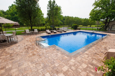 Foto de piscina alargada tradicional grande rectangular en patio trasero con suelo de hormigón estampado