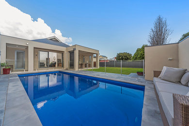 Ispirazione per una piscina monocorsia design rettangolare dietro casa con pavimentazioni in cemento