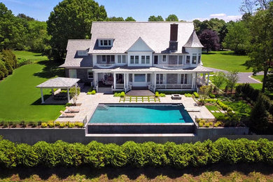 Pool - large traditional backyard stone and rectangular infinity pool idea in New York