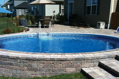 Ejemplo de piscina elevada clásica de tamaño medio a medida en patio trasero con adoquines de ladrillo