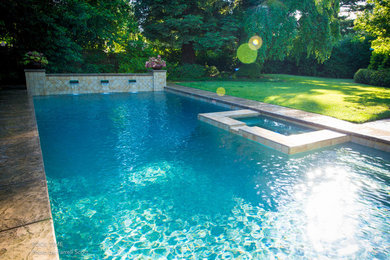 Imagen de piscina con fuente alargada clásica grande rectangular en patio trasero con suelo de hormigón estampado